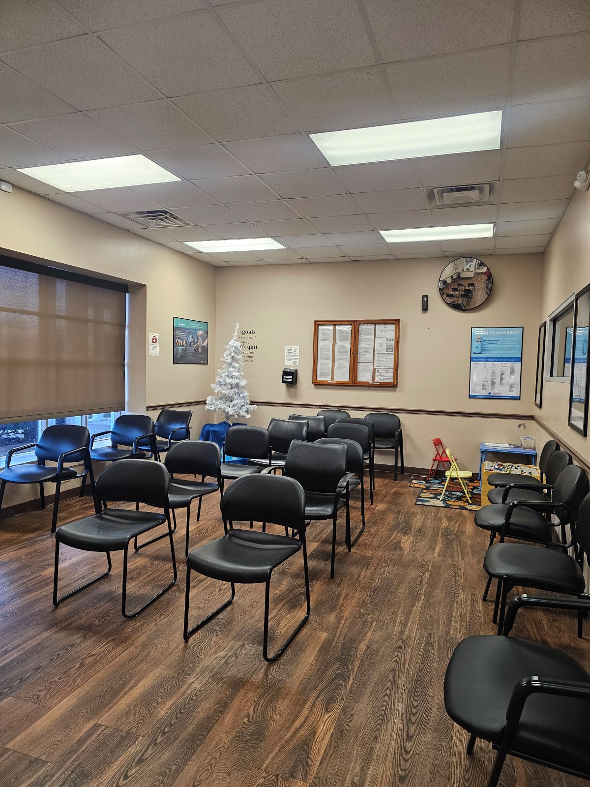 Interior waiting room with multiple black chairs, cream walls, and informational wall displays