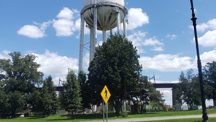 Exterior waterfront park with water tower, recreational facilities, landscaping, and urban skyline backdrop