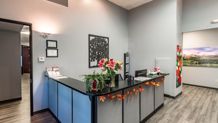 Interior reception area with blue and black desk, decorative flowers in vase, framed artwork, and bright interior lighting