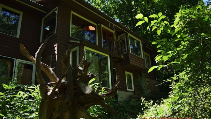 Exterior of two-story treatment facility building with large windows surrounded by dense green trees and foliage