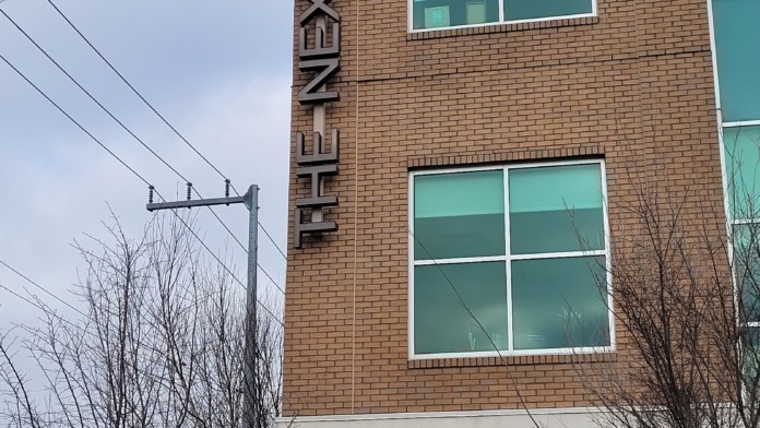 Exterior view showing vertical facility signage on brick building with turquoise windows and winter landscaping.