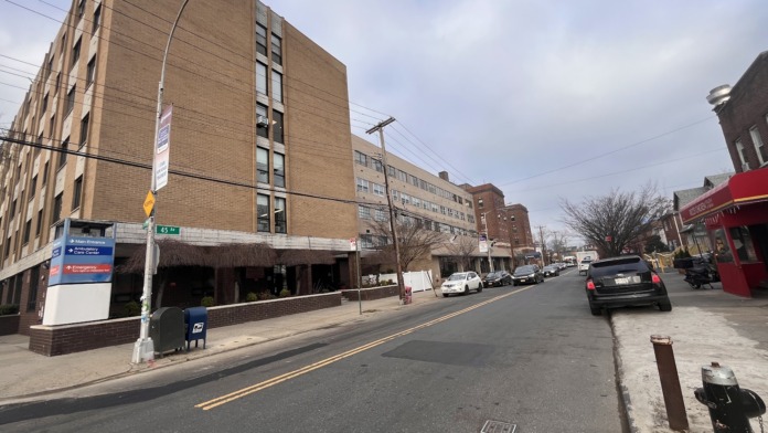 Street-level exterior of multi-story brick building with ground-level storefront and adjacent structures.