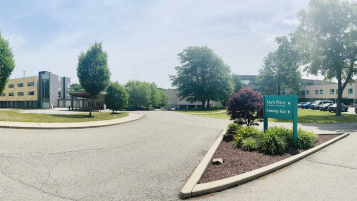 Exterior view of treatment facility campus showing multiple buildings, mature landscaping, trees, and parking areas.