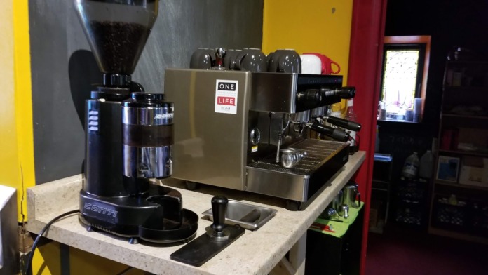 Interior coffee station with espresso machine and grinder on countertop, colorful wall accents.