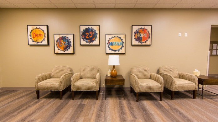Interior common space with beige walls, five armchairs, framed motivational artwork with inspirational words, and side table.
