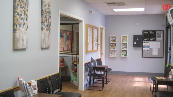Interior common room with tables, chairs, wall art, bulletin boards, and facility materials on display