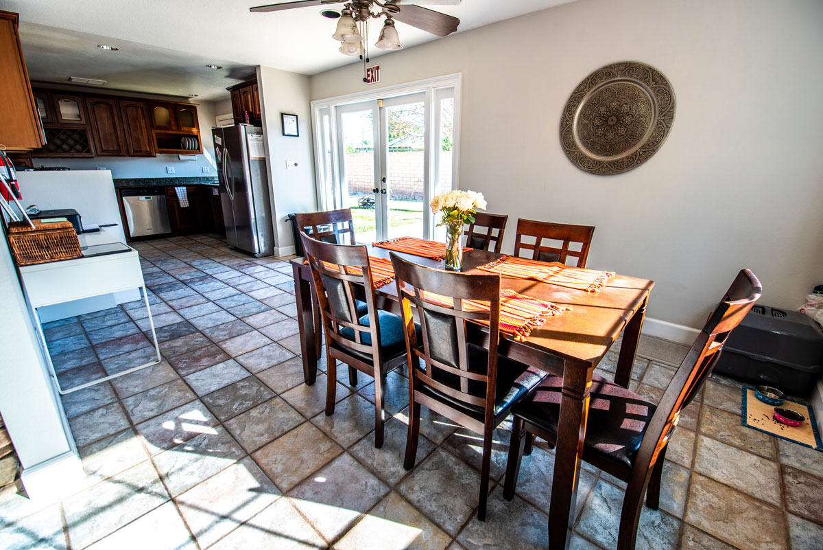 Interior kitchen and dining space with wood table, dining chairs, appliances, and glass doors to patio
