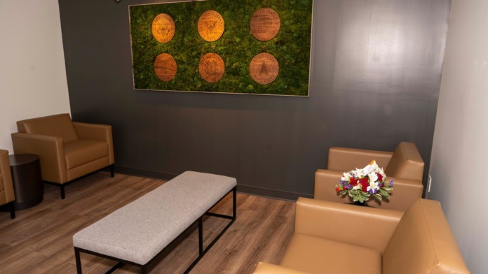 Interior lounge featuring dark walls, tan and orange leather furnishings, decorative moss art installation, and wood flooring