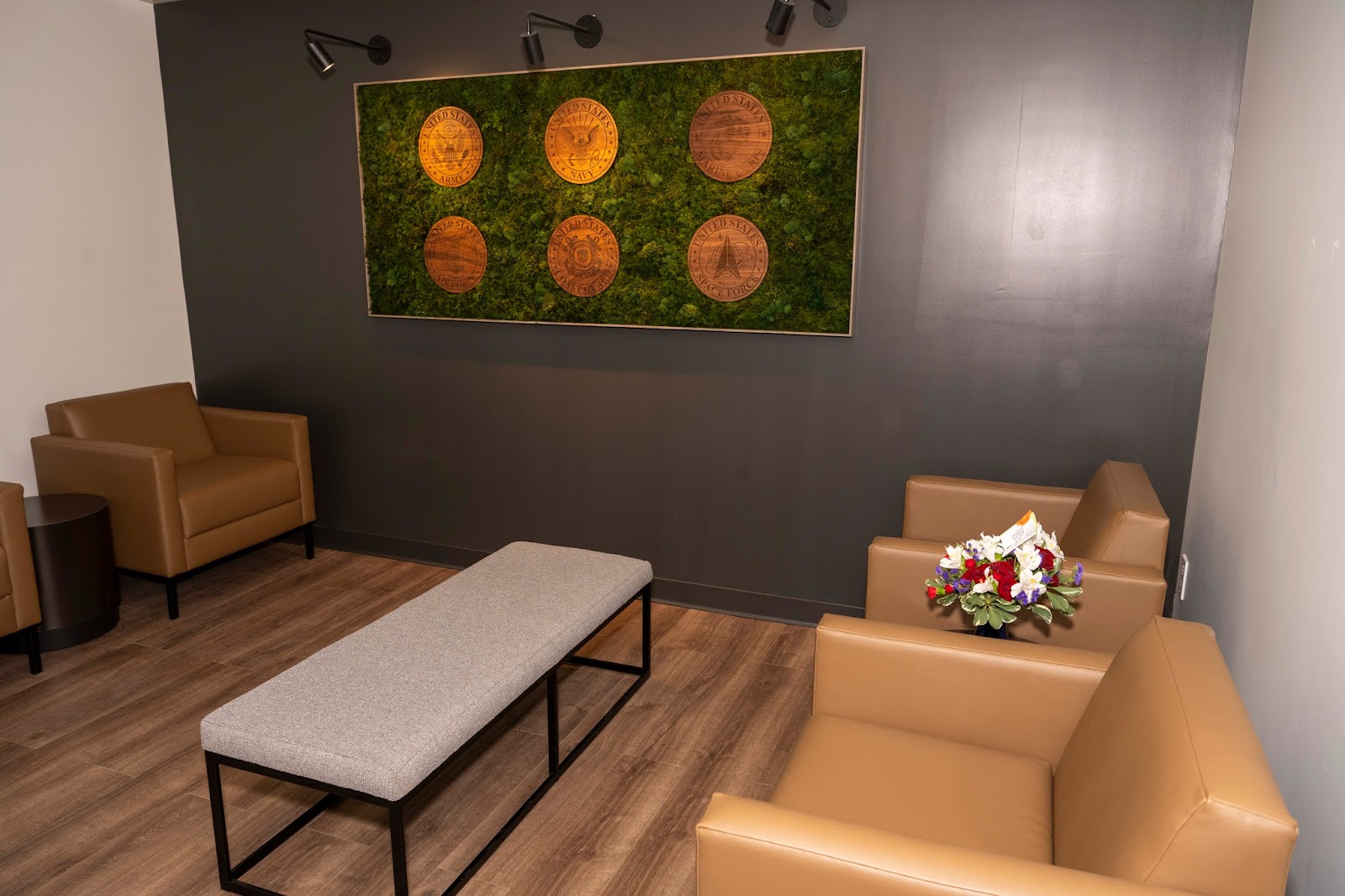 Interior lounge featuring dark walls, tan and orange leather furnishings, decorative moss art installation, and wood flooring