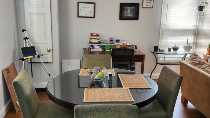 Interior conference room with round black table, green chairs, desk, and framed wall certificates