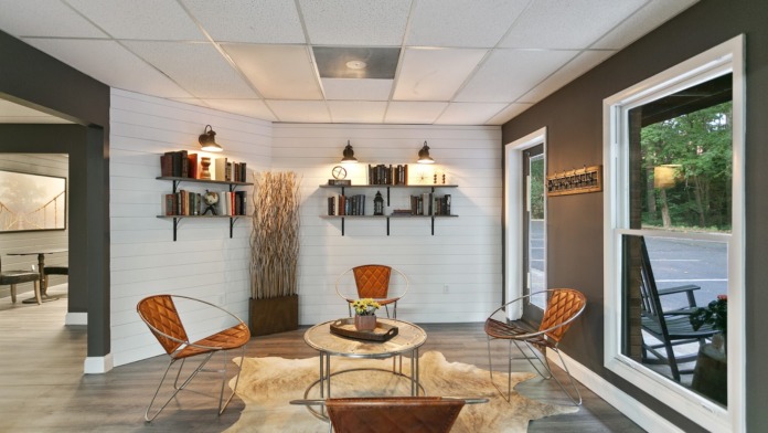 Interior lounge with modern shelving, pendant lighting, round table with chairs, and glass doors opening to patio