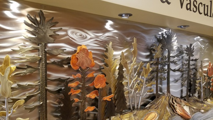 Interior decorative metallic mural featuring stylized botanical flowers and botanical design on wall