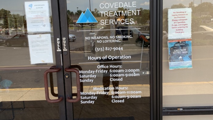 Interior entrance door showing facility address, hours of operation, policies, and contact information on glass