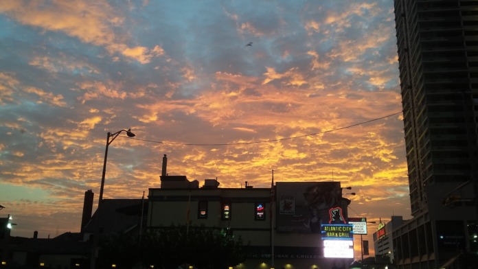 Exterior evening view of facility building with street lamps and adjacent urban structures against sunset
