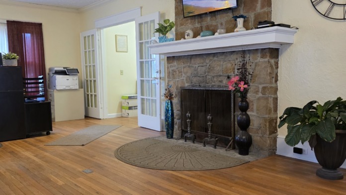 Wide interior view of reception lobby with fireplace, reception desk, storage cabinetry, and entry doors