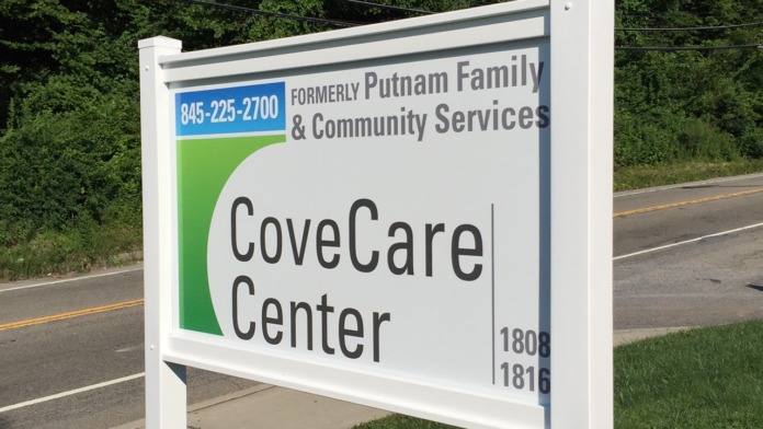 Exterior signage for CoveCare Center on landscaped grounds with road and mature trees in background