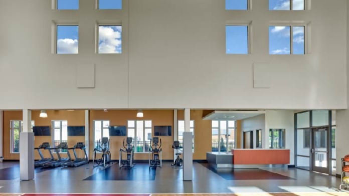 Interior large fitness facility with exercise equipment including treadmills, high ceilings with skylights, and open design.