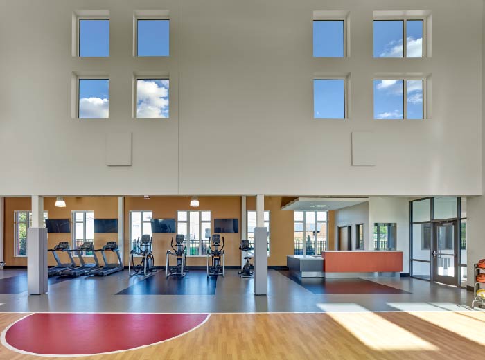 Interior large fitness facility with exercise equipment including treadmills, high ceilings with skylights, and open design.