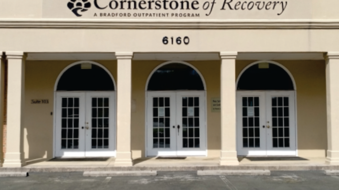 Exterior view of single-story outpatient treatment center with cream facade, three glass entry doors, and suite signage.