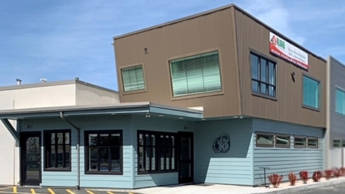 Exterior front view of treatment facility with blue lower level, brown upper level, multiple windows, entrance doors, and parking area.