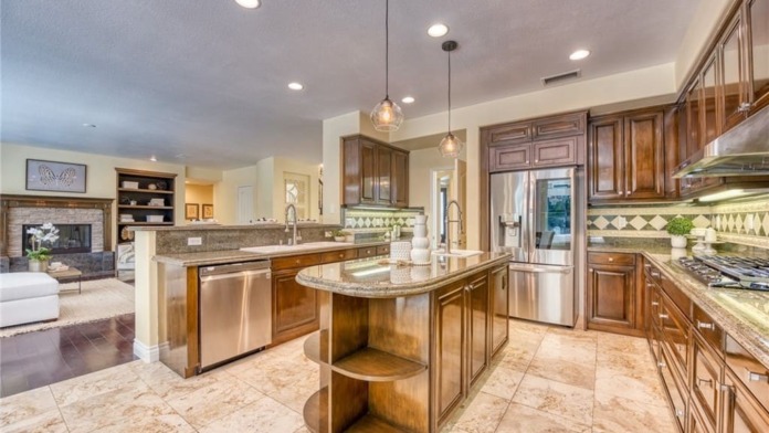 Interior kitchen with wood cabinetry, granite countertops, stainless steel appliances, island, and pendant lighting