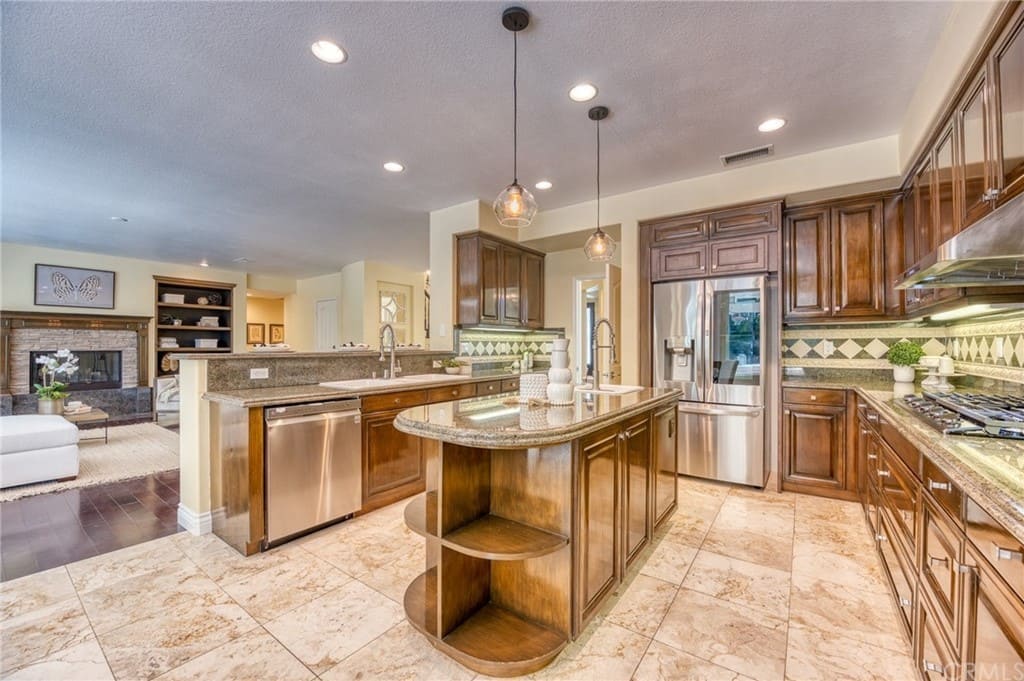 Interior kitchen with wood cabinetry, granite countertops, stainless steel appliances, island, and pendant lighting