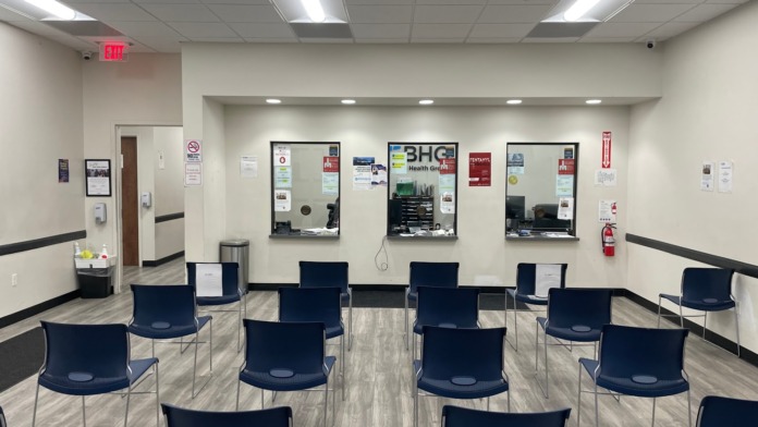 Interior group room with rows of blue chairs, cream walls, BHG logo, fluorescent lighting, and facility signage