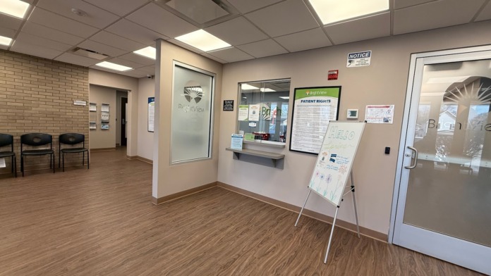 Interior lobby area with cream walls, brick accent, wooden flooring, mounted displays, and service counter.