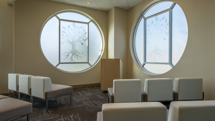 Interior lounge area with large circular windows featuring tree artwork and modern seating arrangements.