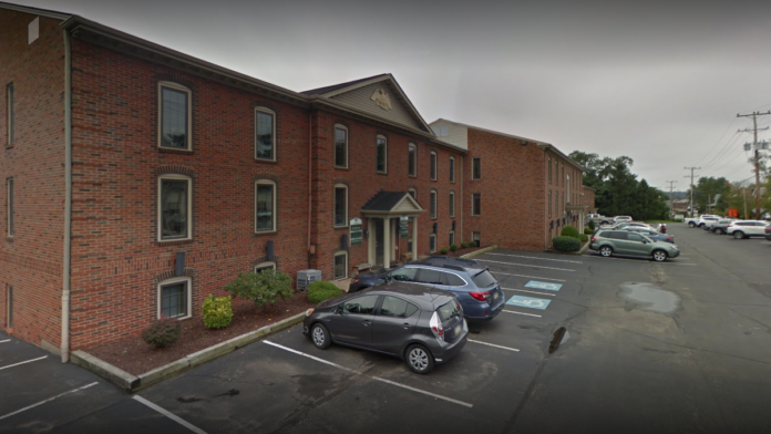 Exterior of three-story red brick treatment facility with front entrance, windows, covered portico, and adjacent parking lot.