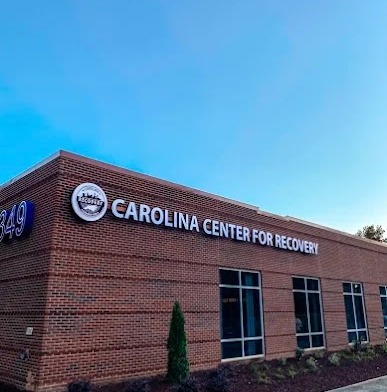 Exterior view of brick treatment facility building with Carolina Center for Recovery signage, landscaped grounds, and clear sky