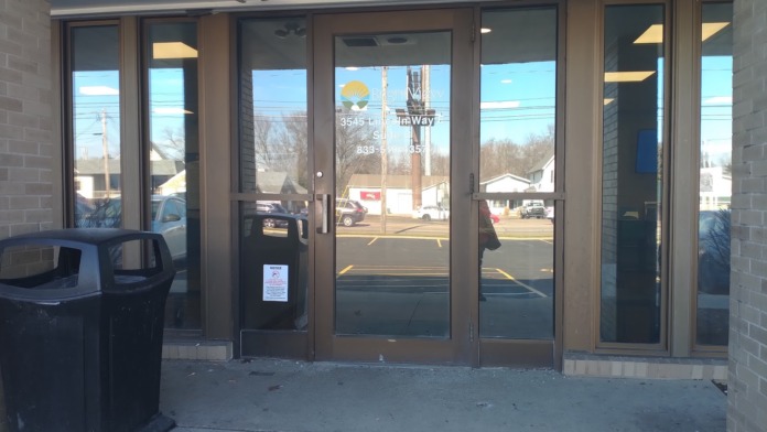 Exterior glass entry doors with tan brick walls and wood trim surrounding main entrance.