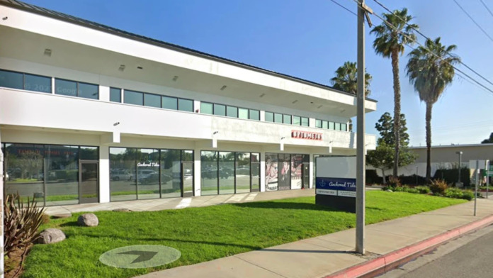 Exterior front view of treatment facility with white trim, glass doors and windows, landscaped grounds, and palm trees