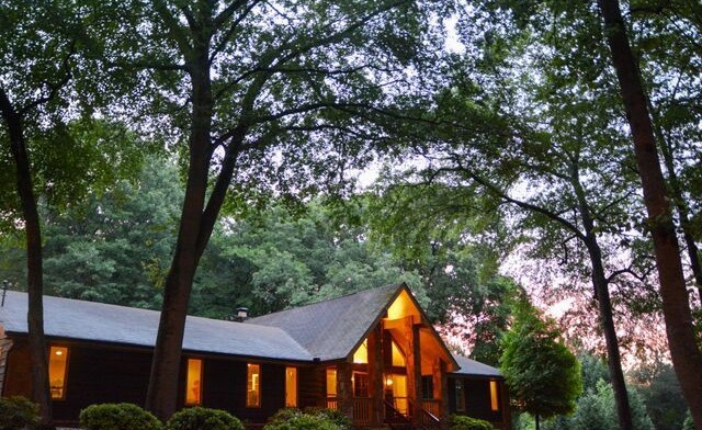 Exterior view of treatment center building illuminated at dusk with landscaped grounds and mature trees