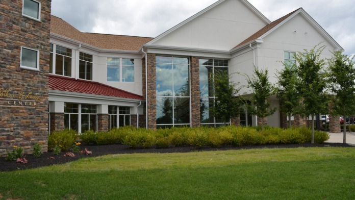 Exterior of modern brick treatment center with large windows, manicured landscaping, and green grounds.