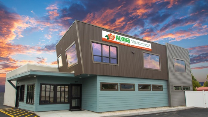 Exterior of Aloha Behavioral Consultants showing front entrance with modern architecture, two-story structure in light blue and brown, dramatic sunset sky.