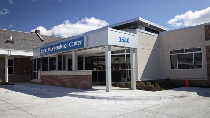 Exterior front entrance of Bryan Independence Center showing brick facade, white canopy entry, and address number 1640 signage