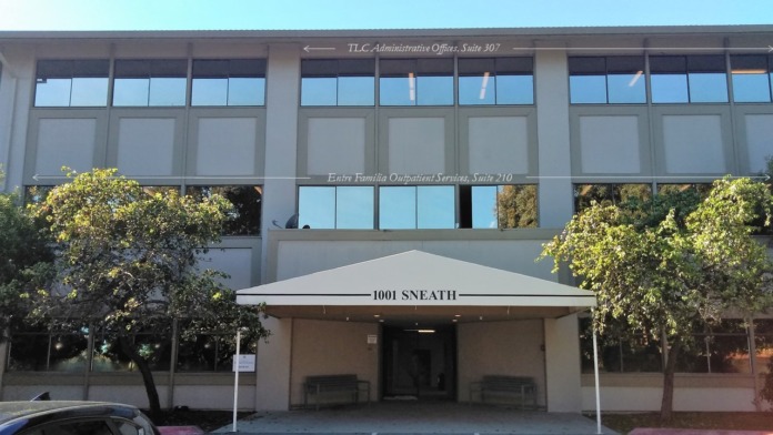 Exterior building facade with gridded windows, signage for administrative offices and outpatient services.