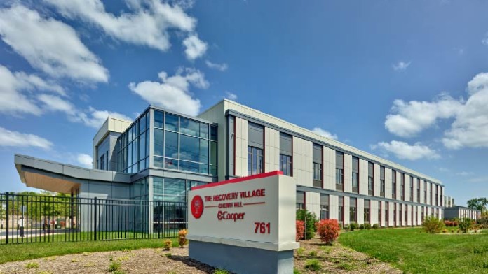 Exterior view of modern treatment facility with contemporary architecture, landscaped grounds, facility signage, and metal perimeter fencing.