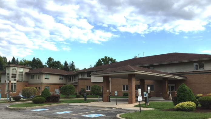 Exterior view of brick treatment facility with multiple connected building sections, covered entrance portico, landscaped grounds, and parking area.