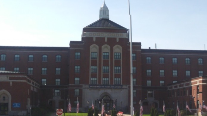 Exterior of large red brick institutional building with central dome and multiple stories