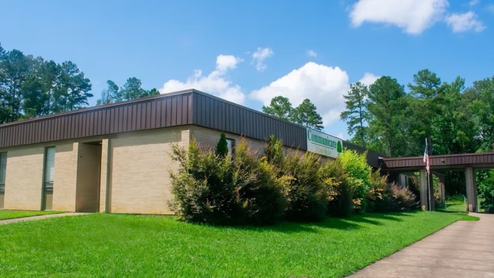Exterior view of modern treatment center building with brick facade, metal roof, landscaped grounds, and entrance walkway.