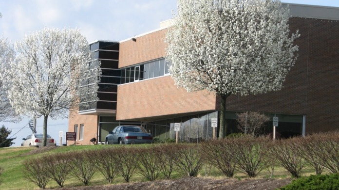 Exterior of treatment center showing two-story brick building with modern design, horizontal windows, and spring landscaping with blooming trees.