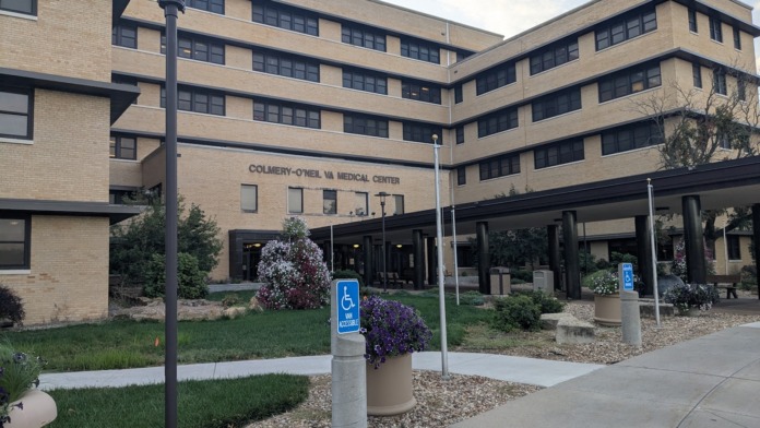 Exterior view of multi-story brick VA medical facility with accessible parking and landscaped grounds