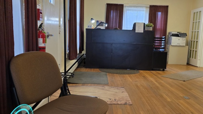 Interior main lobby with black reception desk, fireplace, stone accent wall, and multiple doorways