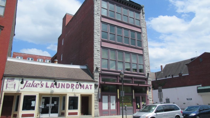 Exterior view of brick treatment facility building with street-level storefront and multi-story facade on downtown street
