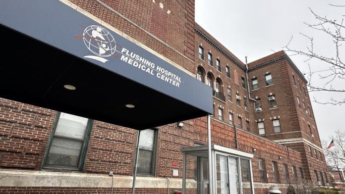 Exterior entrance with Flushing Hospital Medical Center blue awning, brick facade, and glass doors.