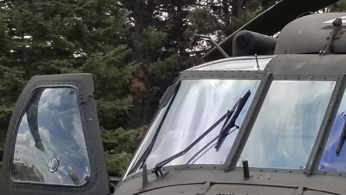 Exterior detail of UH-60 medical evacuation helicopter with red cross marking and green foliage