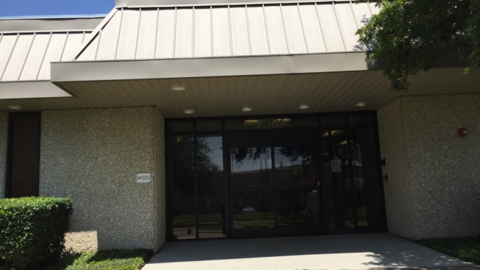 Exterior entrance showing modern covered entry with metal roof, concrete pad, stone facade, and glass doors.