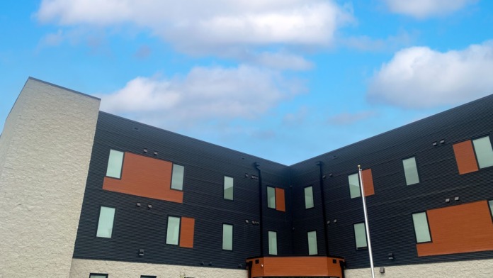 Exterior view of modern Joseph House facility featuring light brick and dark metal siding with orange and teal window accents
